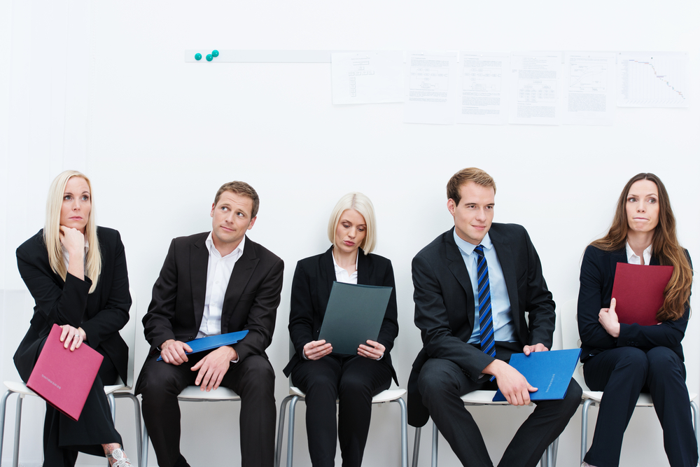 Group of applicants for a vacant post or corporate job sitting in a long line with folders containing their credentials carefully ignoring each other-1